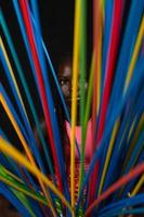 portrait of young pretty african teenager stands behind long colored straws photo