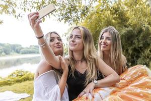 female millennial girlfriends taking a selfie outdoors on the river photo
