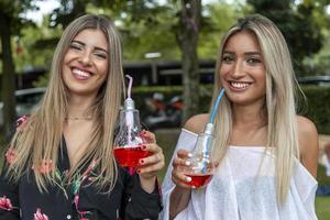 couple of young pretty women drinking fresh and energetic red juice photo