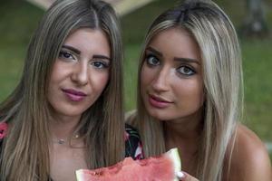 couple of young beautiful women eating a slice of fresh watermelon photo