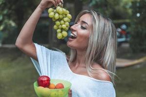 young pretty woman is eating fresh fruit on vacation photo