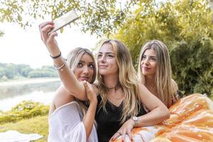 hembra milenario novias tomando un selfie al aire libre en el río foto