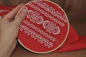 Hand embroidery cross on red cloth with white thread photo