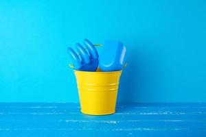 yellow childrens metal bucket and plastic shovel and rake photo