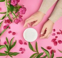 hands of a young girl with smooth skin and a jar with thick cream photo