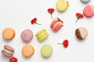 baked macarons with different flavors and rosebuds on a white background photo