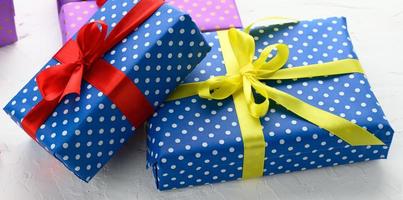 boxes packed in festive blue paper and tied with silk ribbon on white background, birthday gift, surprise photo