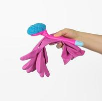 female hand holds pink cleaning gloves and a brush on a white background photo