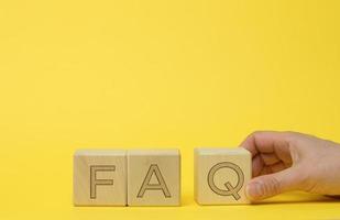 inscription FAQ frequently asked questions on wooden blocks on a yellow background photo