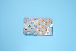 redondo amarillo pastillas en un ampolla paquete en un azul fondo, parte superior ver foto