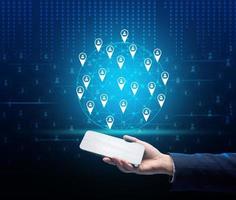 a female hand holds a smartphone and a holographic screen with a world map and friends marks. Information exchange, social networks. Business development around the world photo