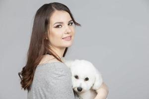 A beautiful young woman is holding her bichon puppy. Love between owner and dog. The girl is playing with the dog. photo