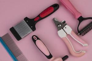 Tool for the groomer on a pink background. Dog grooming accessories. Combs and brushes for animals. View from above photo