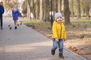 un pequeño chico carreras a lo largo el camino en el parque. foto