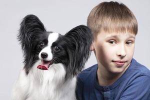 pequeño chico con un Papillon perro. mascota con dueño. niño con un gracioso cachorro. foto