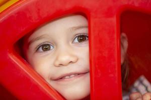 A little girl peeks through a hole. The face of a child in a circle. photo