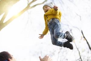 un joven contento padre lanza arriba su pequeño hijo. foto