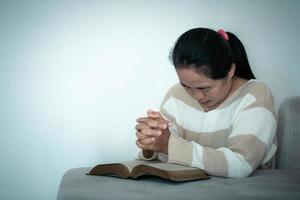 woman kneeling and praying in modern house at sunset time. Female catholic prayer worship to God wish a better life in home at dawn with believe faith. concept of worshipers kneeling. photo