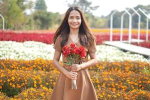 Asian woman smiling happily among beautiful flowers photo