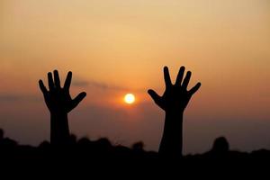 silhouette of human hand raised to make a wish, sunset background photo