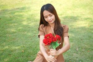 asiático mujer sonriente felizmente entre hermosa flores foto