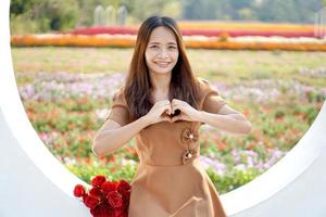 asiático mujer sonriente felizmente entre hermosa flores foto