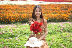 Asian woman smiling happily among beautiful flowers photo