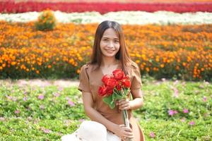 Asian woman smiling happily among beautiful flowers photo