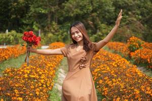 Asian woman smiling happily among beautiful flowers photo