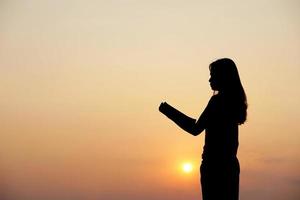 silueta de un mujer participación un computadora puesta de sol antecedentes foto