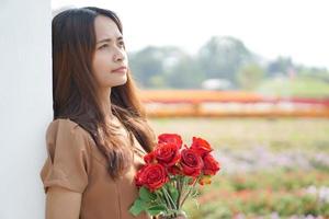 Asian woman smiling happily among beautiful flowers photo