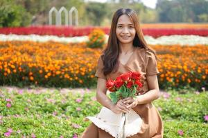 Asian woman smiling happily among beautiful flowers photo