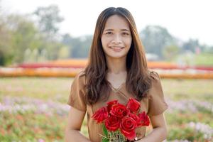 asiático mujer sonriente felizmente entre hermosa flores foto