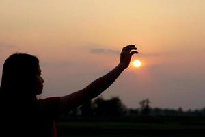 silhouette of human hand raised to make a wish, sunset background photo
