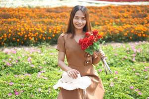 Asian woman smiling happily among beautiful flowers photo