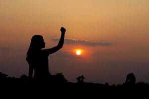 silhouette of human hand raised to make a wish, sunset background photo