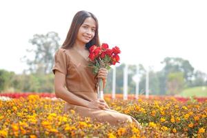 asiático mujer sonriente felizmente entre hermosa flores foto