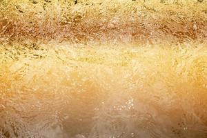 Blurred transparent Yellow Gold colour clear calm water surface texture with splashes and bubbles. Trendy abstract nature background. Water waves in sunlight. water background, oil photo