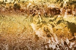 Blurred transparent Yellow Gold colour clear calm water surface texture with splashes and bubbles. Trendy abstract nature background. Water waves in sunlight. water background, oil photo