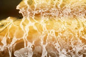 Blurred transparent Yellow Gold colour clear calm water surface texture with splashes and bubbles. Trendy abstract nature background. Water waves in sunlight. water background, oil photo