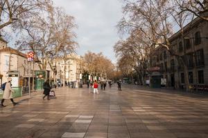 People on La Rambla street surrounded with bare trees and buildings in Barcelona photo