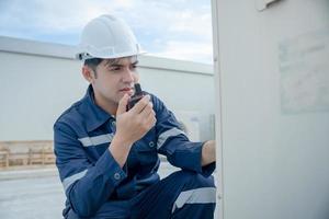 Asian maintenance engineer works on the roof of factory. contractor inspect compressor system and plans installation of air condition systems in construction. technology, online checking. photo