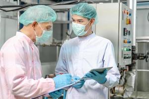 A quality supervisor or food or pharmaceutical technician discuss about process control of food and drugs before send product to the customer. Production leader recheck parameter and productivity. photo