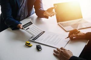 Hand holding car keys and car rental concept A close-up view of the agent, giving the customer the car keys after signing the lease, rental form and car name. photo