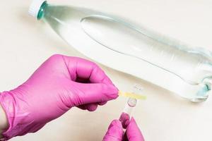 gloved hand holds wet litmus paper on test tube photo