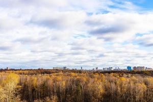 cloudy sky over forest and city in autumn photo