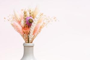 bouquet of dried plants in neck of bottle on pink photo