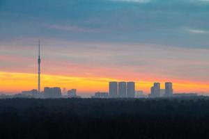 early winter dawn over dark forest and city photo