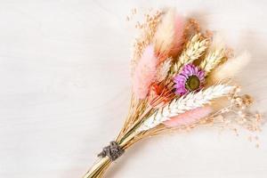 dried flowers and spikelets on light brown board photo