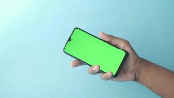 Close up of young man hand using smart phone with green screen video